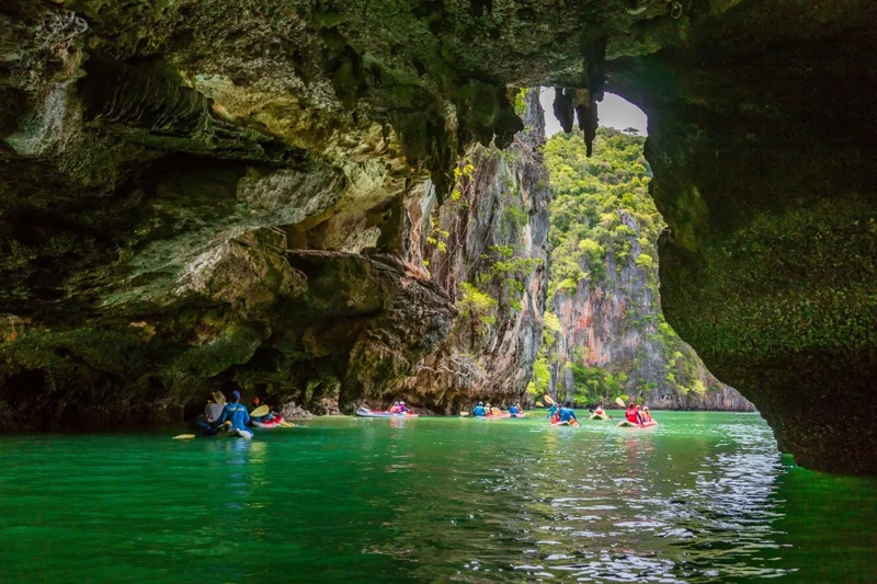 "Kayakers exploring the caves of Hong Island, surrounded by lush greenery in Phuket.