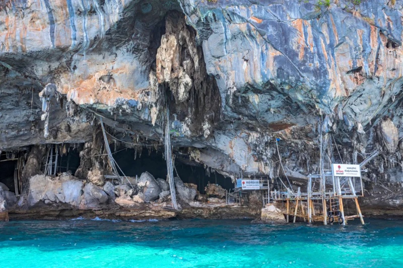 Cave entrance on Phi Phi Island, with crystal clear water and lush green surroundings.