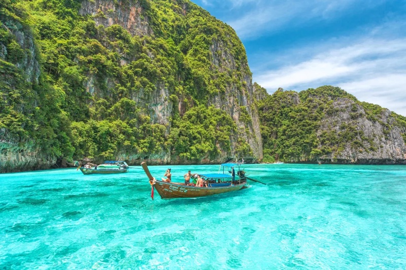 Clear turquoise waters of Phi Phi Island with boats sailing along the coastline.