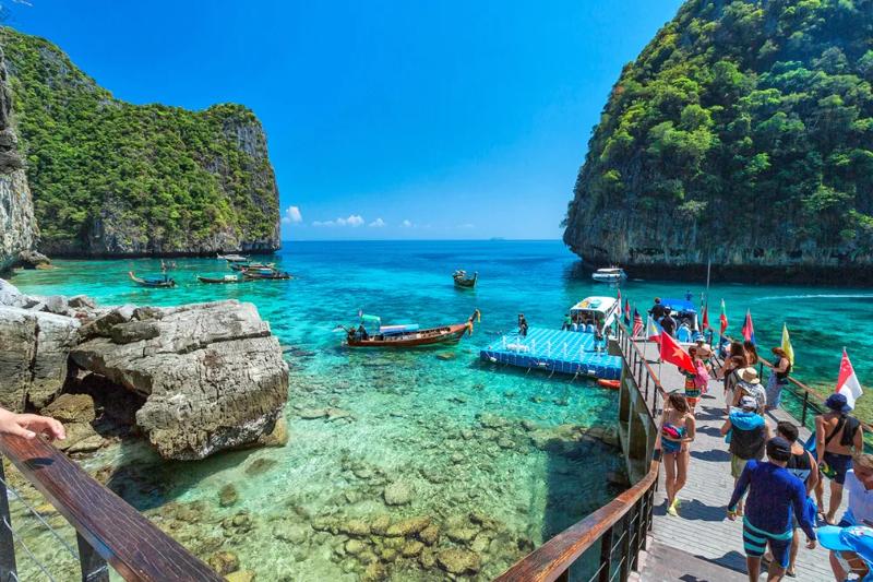 Fishing boats lined up on the shore of Phi Phi Island, with beautiful tropical scenery.