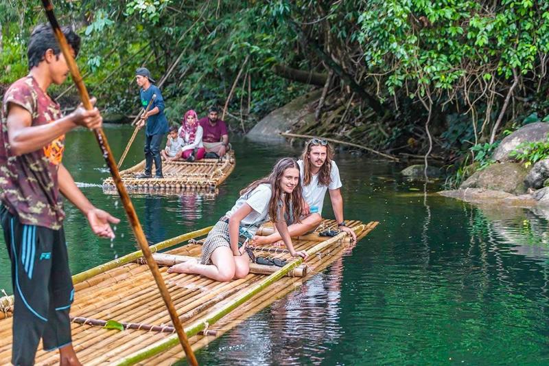 Experience the tranquility of bamboo rafting in Thailand, gliding down crystal-clear rivers surround