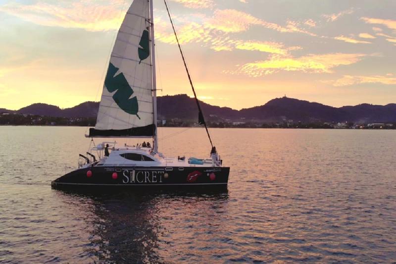 Private sailing boat at sunset, cruising through the serene ocean waters.