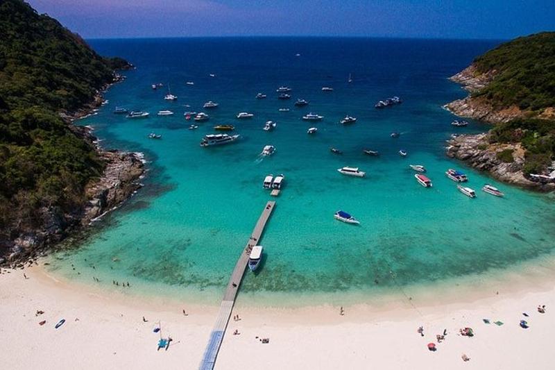Racha Island beach view, featuring golden sand, clear turquoise waters, and boats anchored along the
