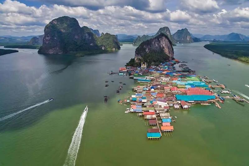 Floating village at James Bond Island, showing colorful buildings and calm waters.