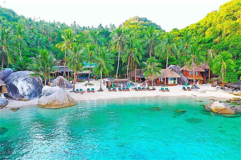 Jansom Bay on Koh Tao, offering turquoise waters and a serene beach surrounded by lush greenery.