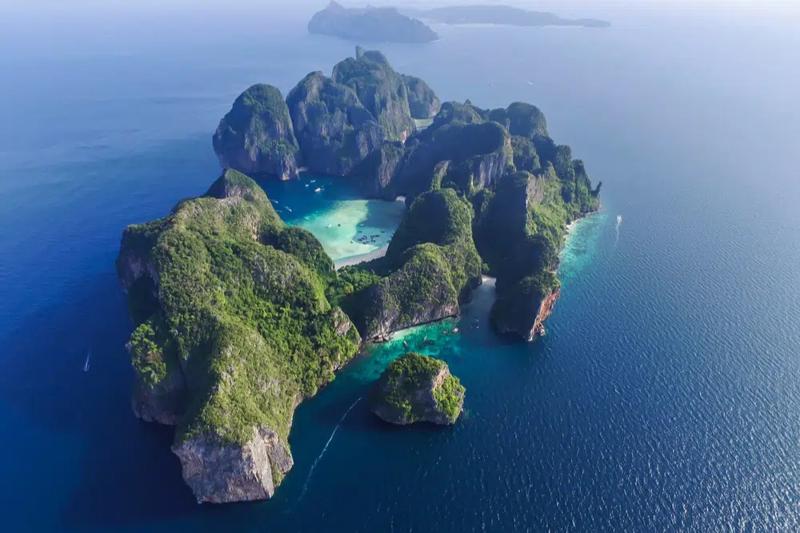 Island landscape in Thailand with green hills and clear blue ocean stretching to the horizon, offeri