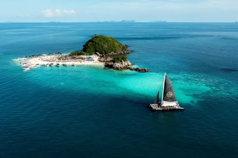 Aerial view of a private island in Thailand with turquoise waters and a sailboat in the foreground.