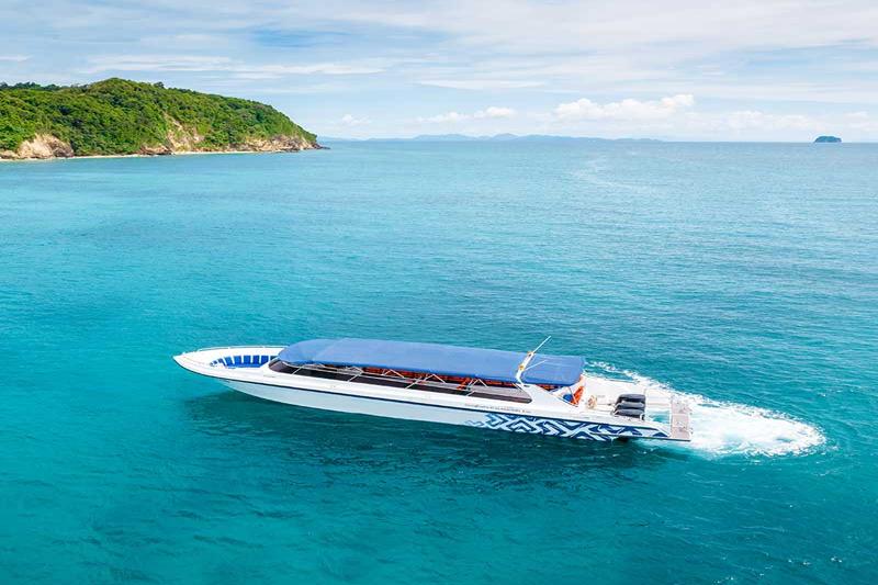 A premium speed boat cruising in the clear waters near Surin Island, Phuket, with green hills and co