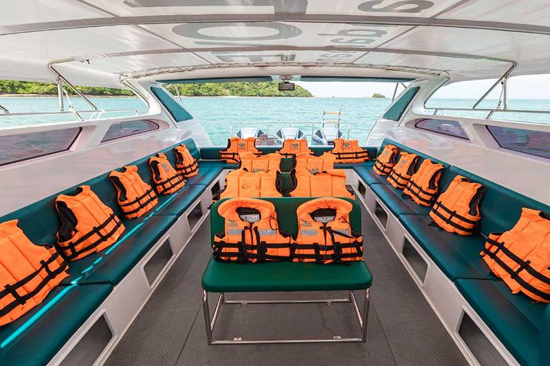 Interior of a speed boat with orange life jackets neatly arranged along the seats, with a clear view