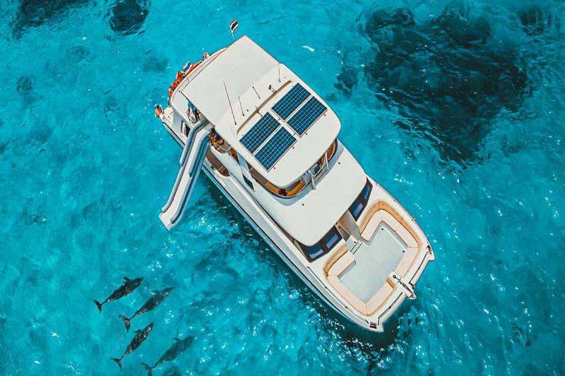 A luxury yacht named Indigo by 7 Plus with solar panels, featuring a water slide, cruising through c