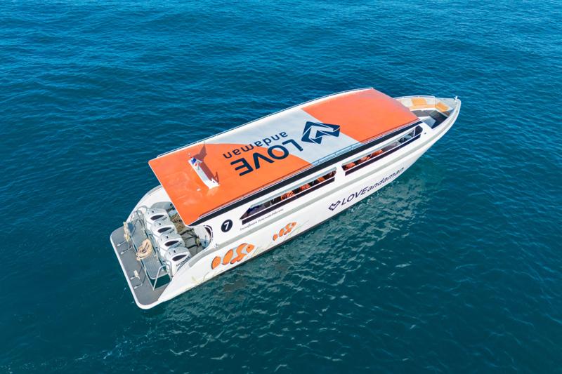  Love Andaman speed boat named Okeanos cruising through clear blue water with visible orange life ja