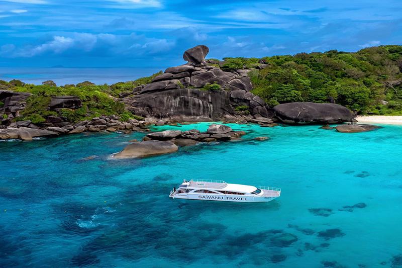 A Sawanu luxury yacht cruising in the crystal-clear waters near the Similan Islands, with dramatic r