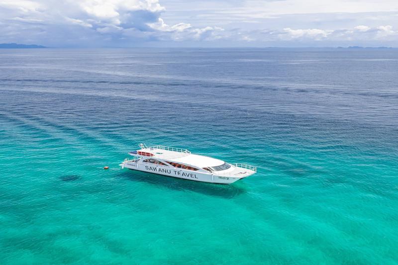  Sawanu Travel yacht cruising in the turquoise waters near Phi Phi Island, with clear blue skies and