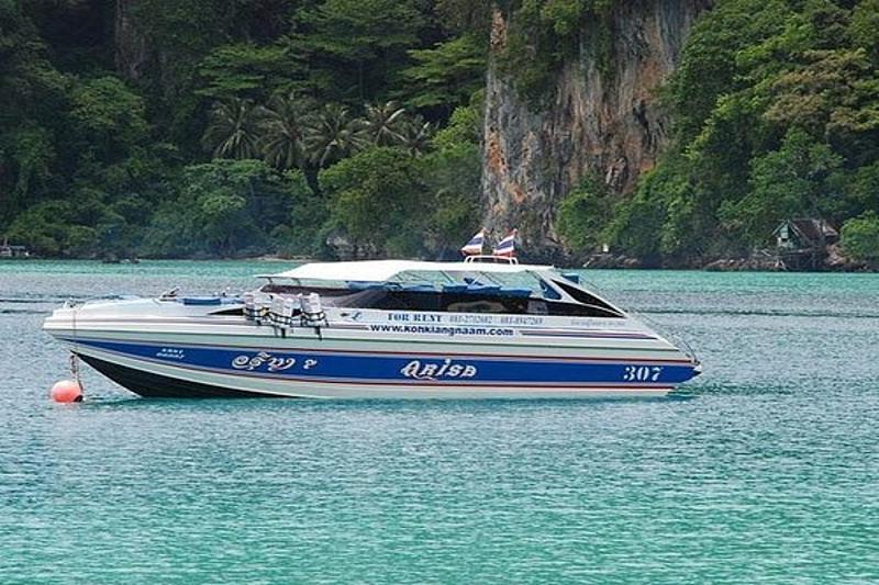 A premium speed boat cruising in the crystal-clear waters near James Bond Island, with lush greenery