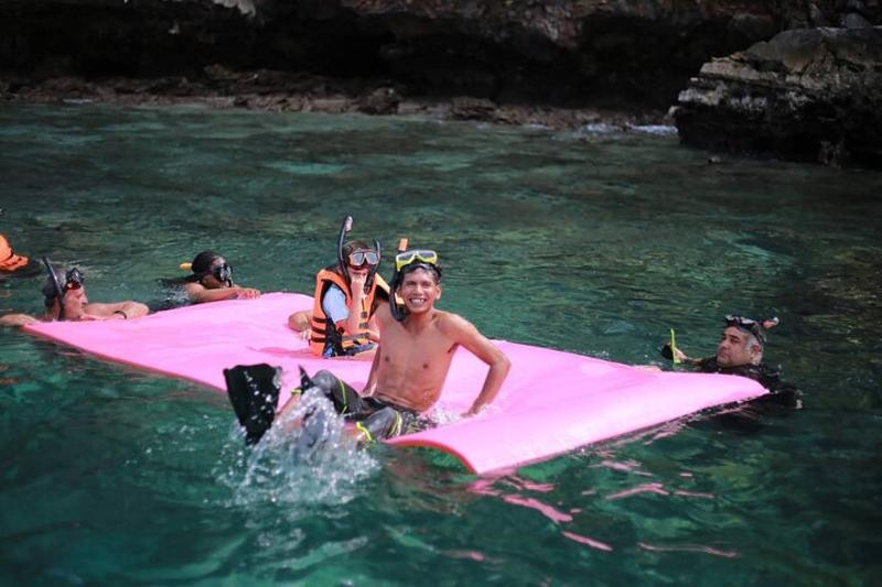 A Tip Top speed catamaran cruising through the waters of Phang Nga Bay, with dramatic limestone clif