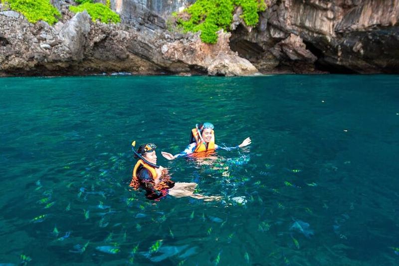 Tourists enjoying snorkeling in the clear waters of Phuket´s islands, with colorful marine lif