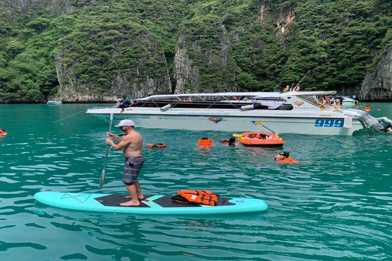 A person paddleboarding on clear turquoise water at Pileh Lagoon Phi Phi Islands during a tropical t