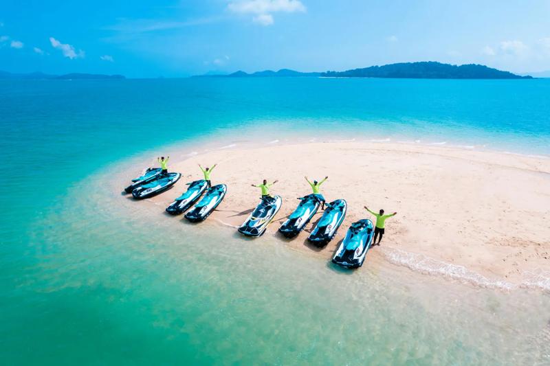 A view of a beautiful beach in Phuket, with jet skis parked on the sand and clear blue waters in the