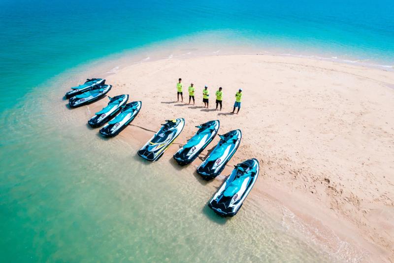 A sunny day on the beach in Phuket, with jet skis available for rent and clear blue skies overhead.
