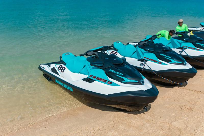 People riding jet skis along a sandy beach in Phuket, enjoying the clear turquoise waters and sunny 