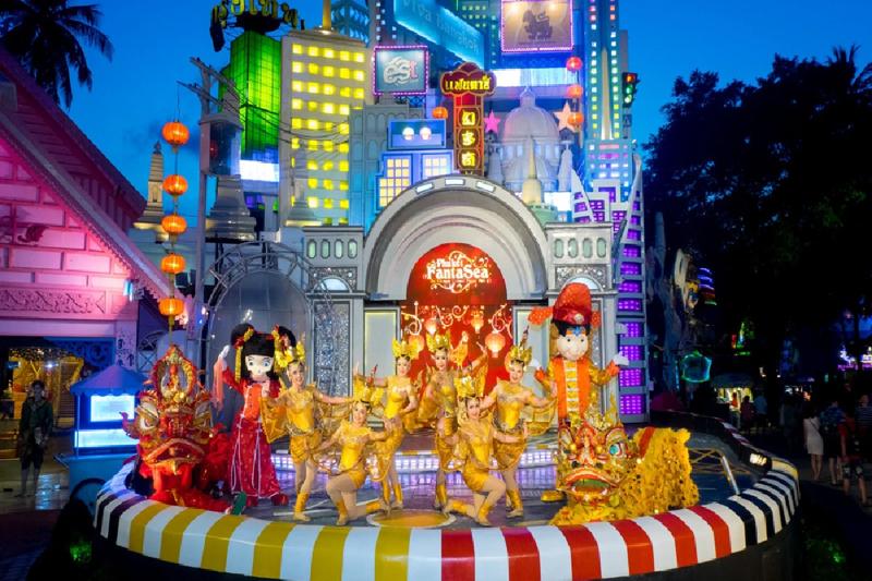  Performers in colorful costumes entertaining the crowd with an outdoor show at Phuket Fantasea.