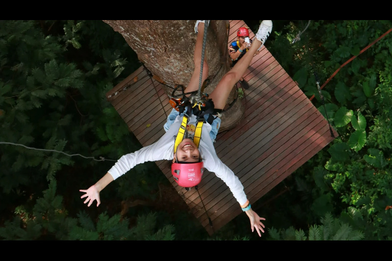 A person ziplining high above the trees at Hanuman World Phuket, enjoying an adrenaline-filled ride.