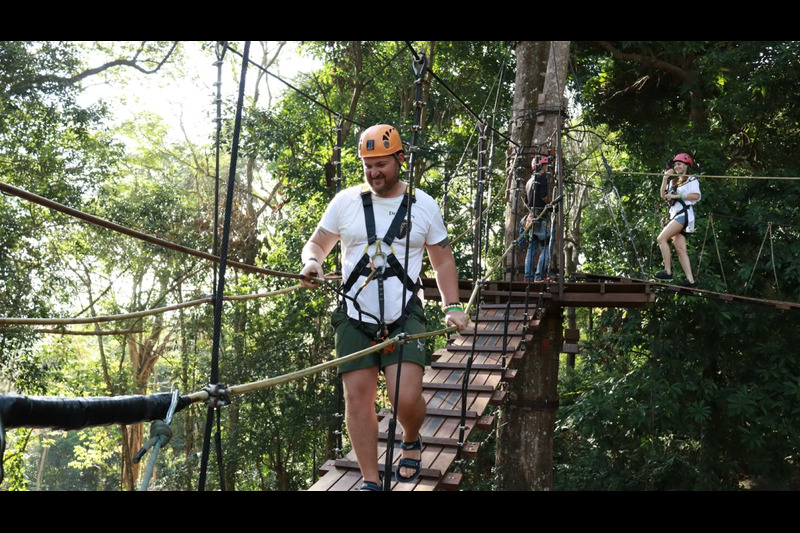 A thrill-seeker in full safety gear gliding across the zipline at Hanuman World, with a breathtaking