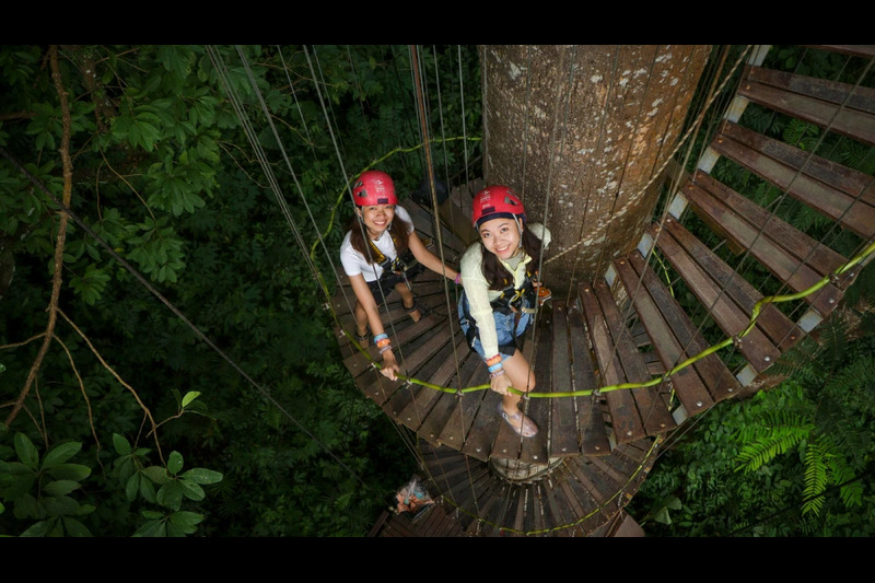A visitor carefully stepping along the glass skywalk at Hanuman World Phuket, enjoying panoramic jun